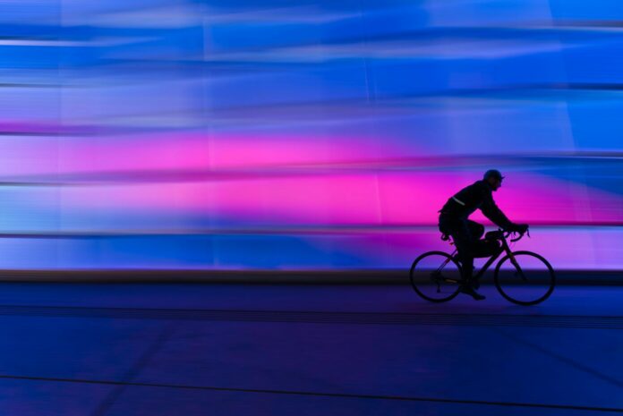 A cyclist's silhouette zooms past a colorful urban background. Ideal for fitness and city life themes.